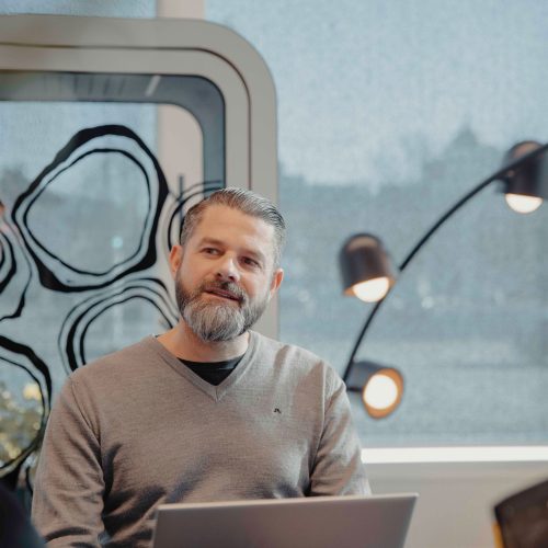 Projektledare i möte i modern kontorsmiljö, fokuserad på planering och styrning av industriprojekt. Sittande med laptop och samtal i fokus.